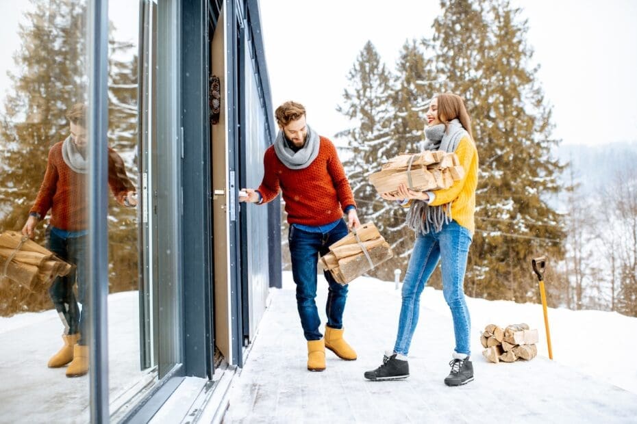 Young couple near their modern house in the mountains during the winter