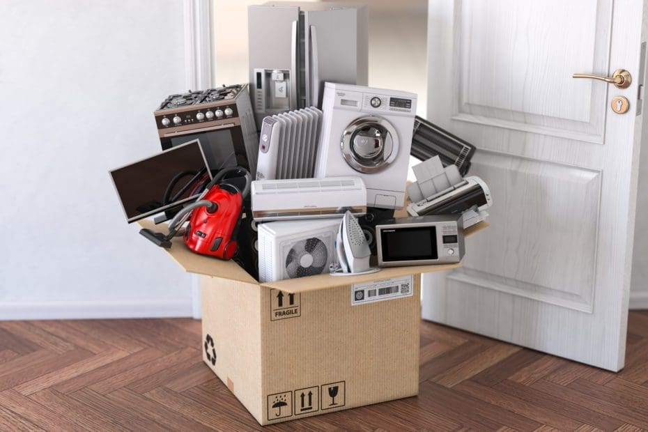Open cardboard moving box with multiple appliances stacked on top of it