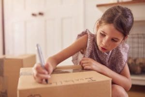 Girl Labelling Boxes Getting Ready For Moving Day Into New Home